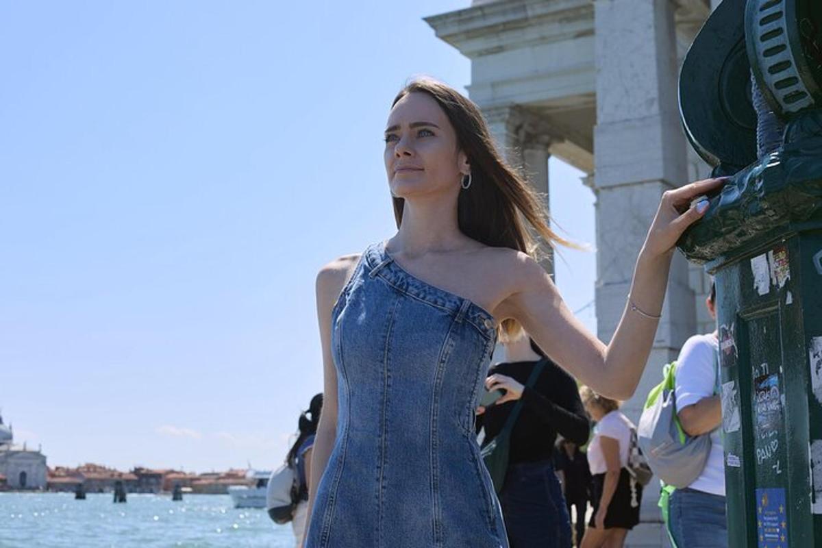 Una mujer con un vestido azul apoyada en un poste.