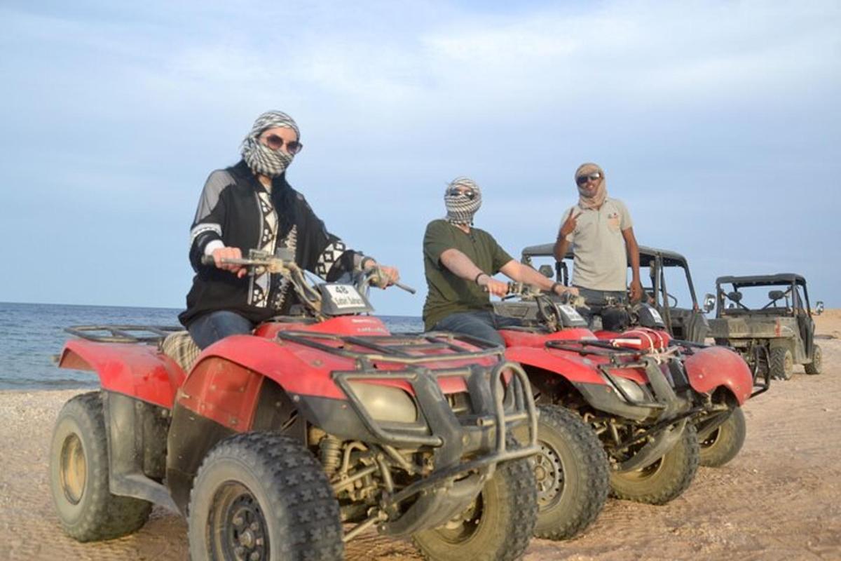 tiga lelaki sedang menunggang atv di pantai