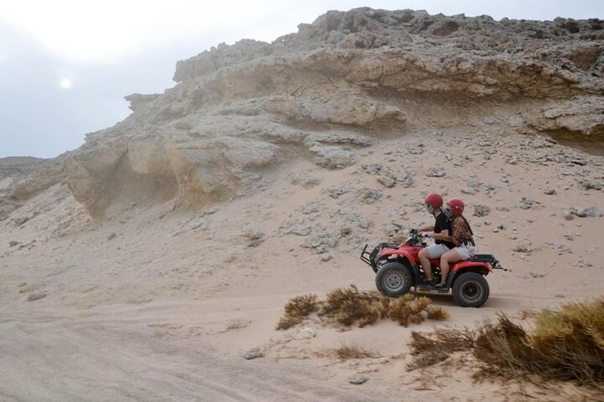 dua orang menunggang basikal quad di padang pasir
