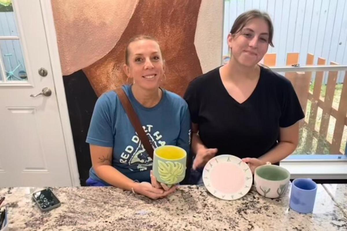 two women sitting at a table with cups and plates