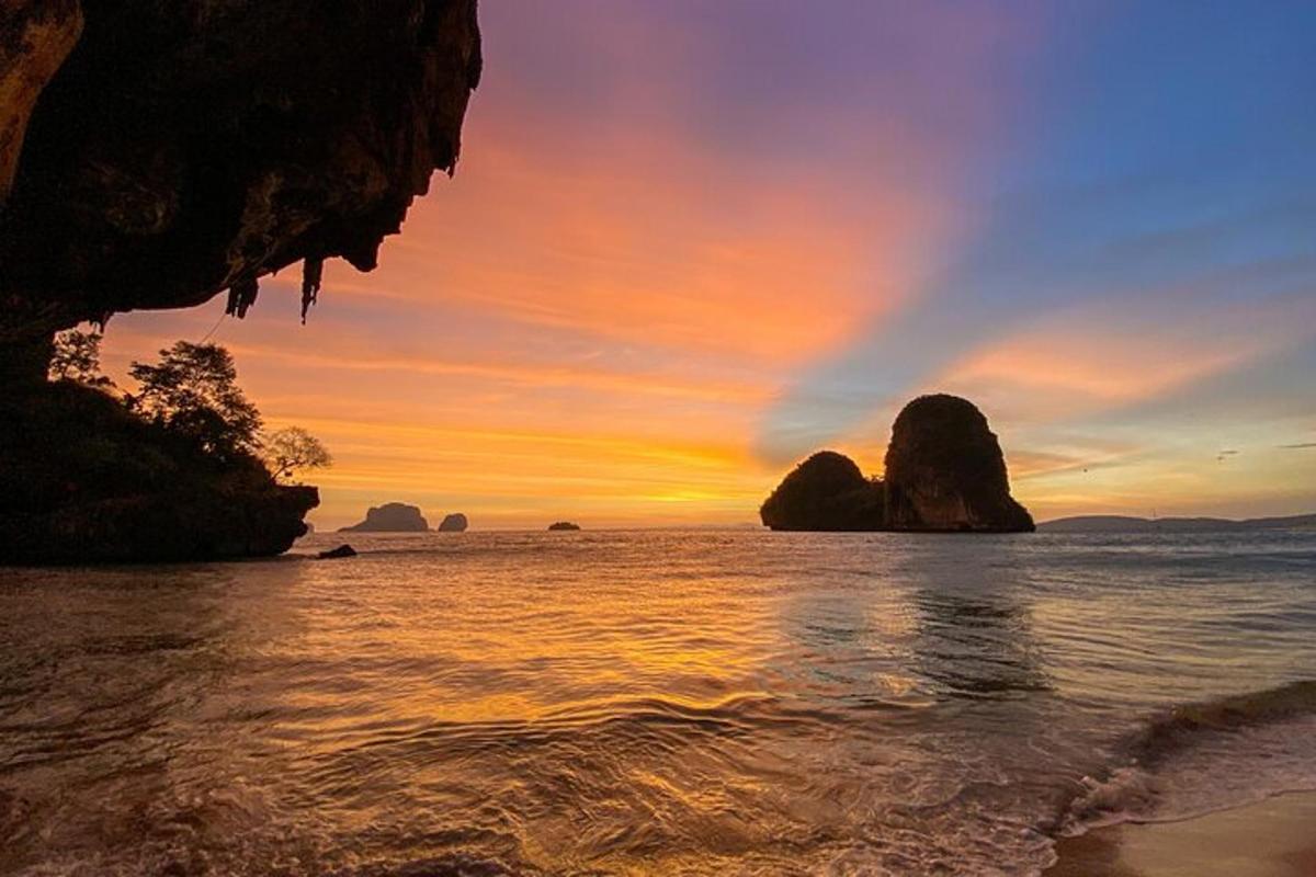 a sunset over the ocean with rocks in the water