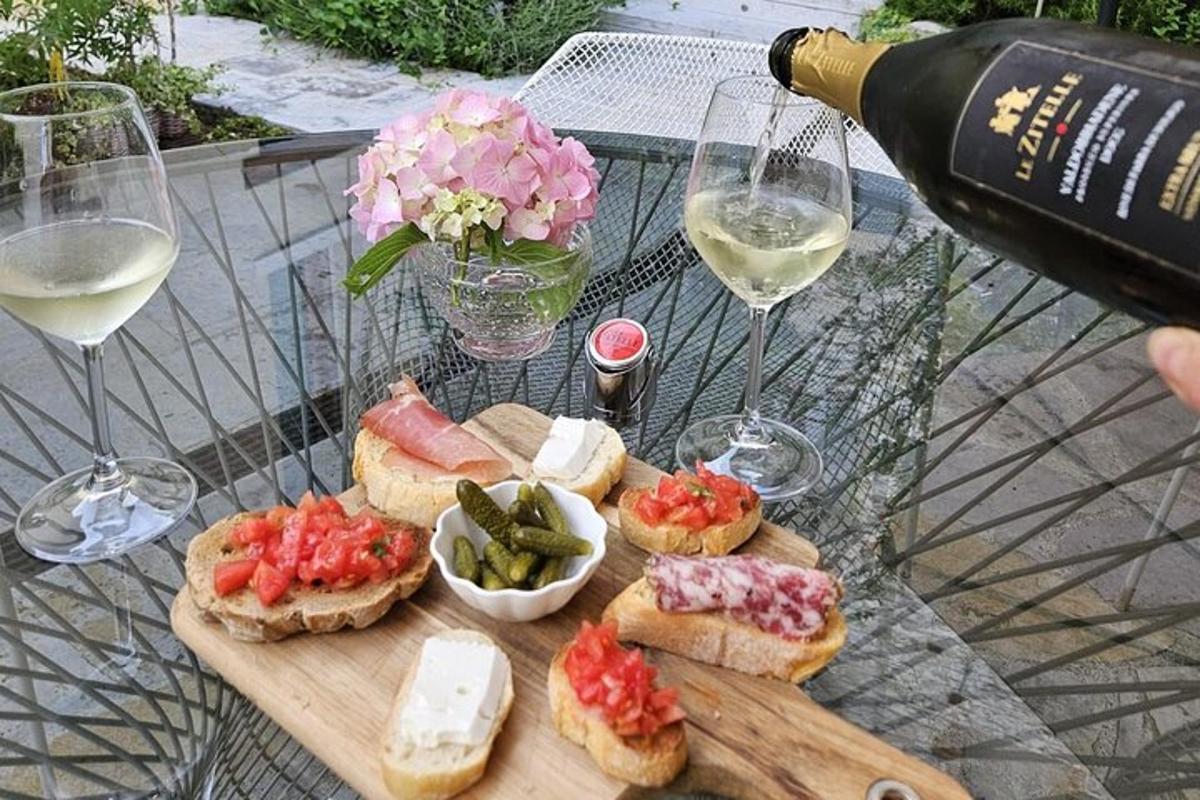 una persona che versa una bottiglia di vino su un tavolo con panini e bicchieri di vino