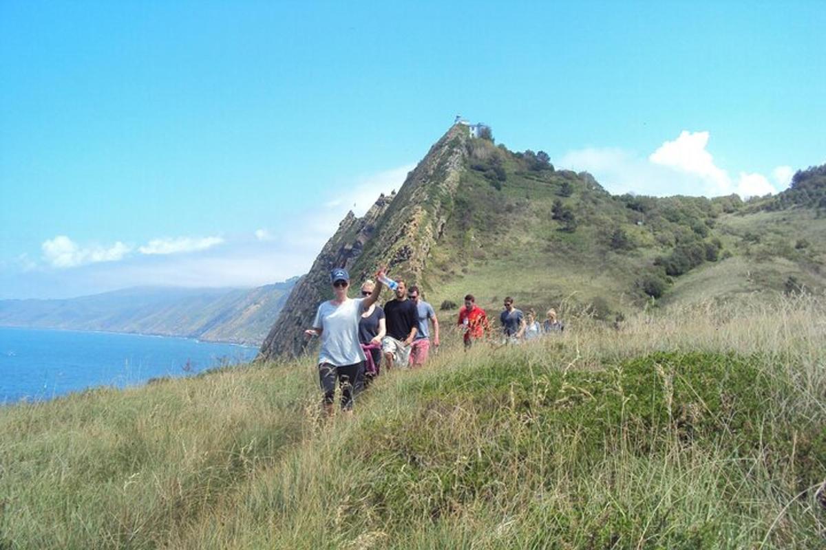 un grup de persones caminant per un turó a prop de l'aigua