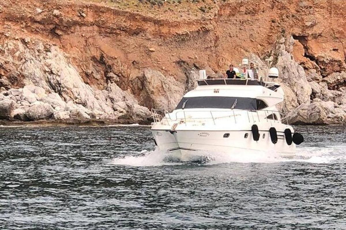 a white boat in the water near a cliff