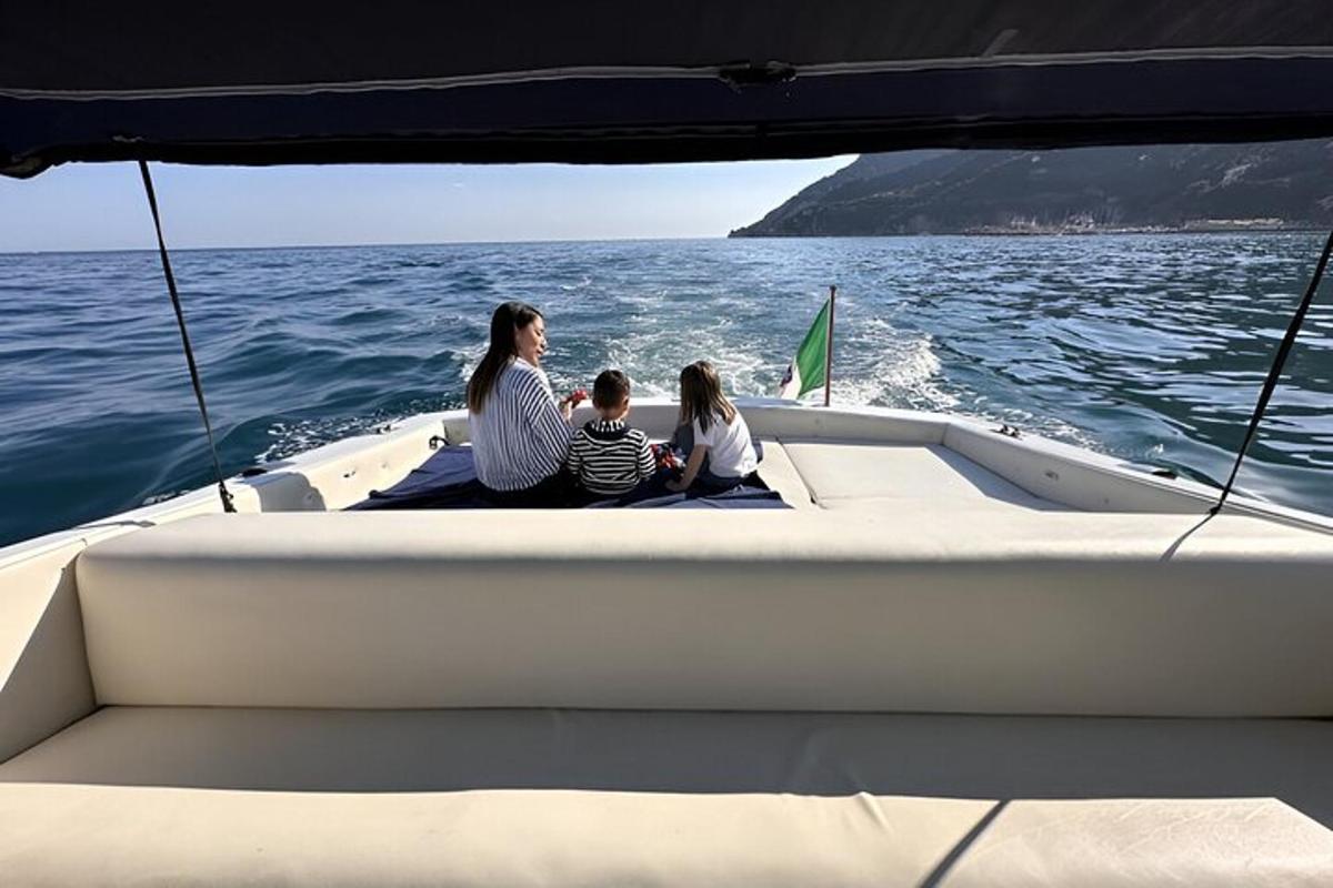 Una mujer y dos niños sentados en la parte trasera de un barco