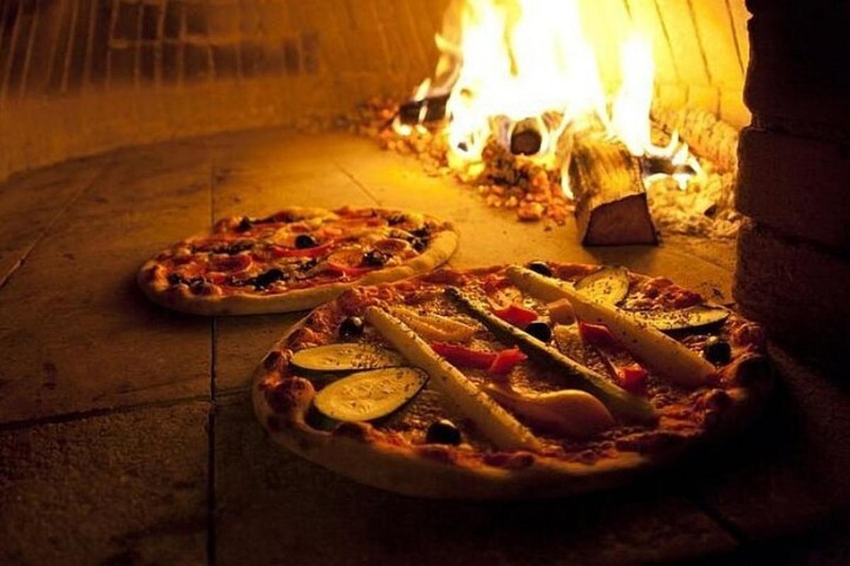 Dvě pizzy leží v peci na oheň