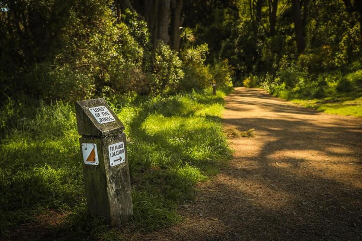 a sign in the grass next to a dirt road