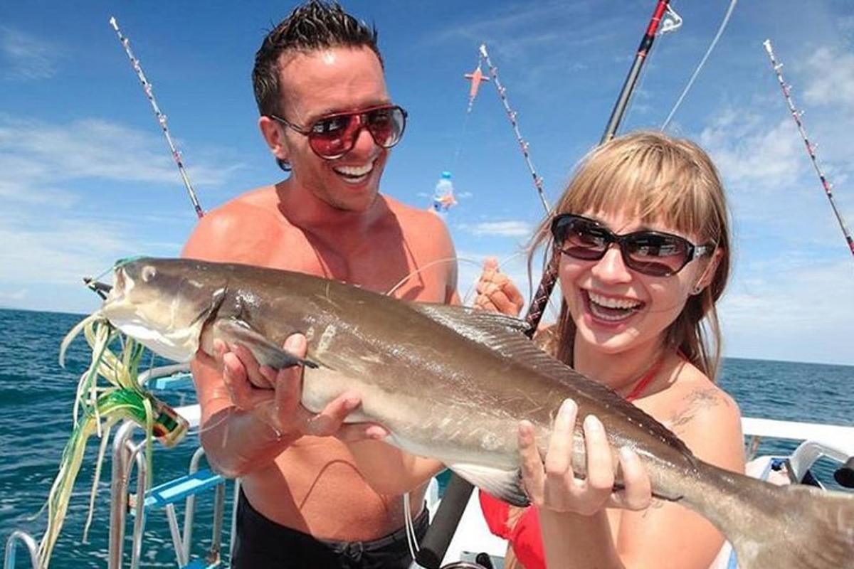 un uomo e una donna che tengono un pesce su una barca