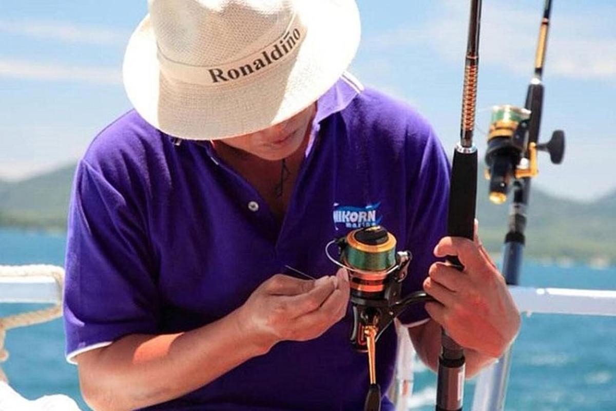 un uomo con un cappello che guarda una telecamera con un pesce