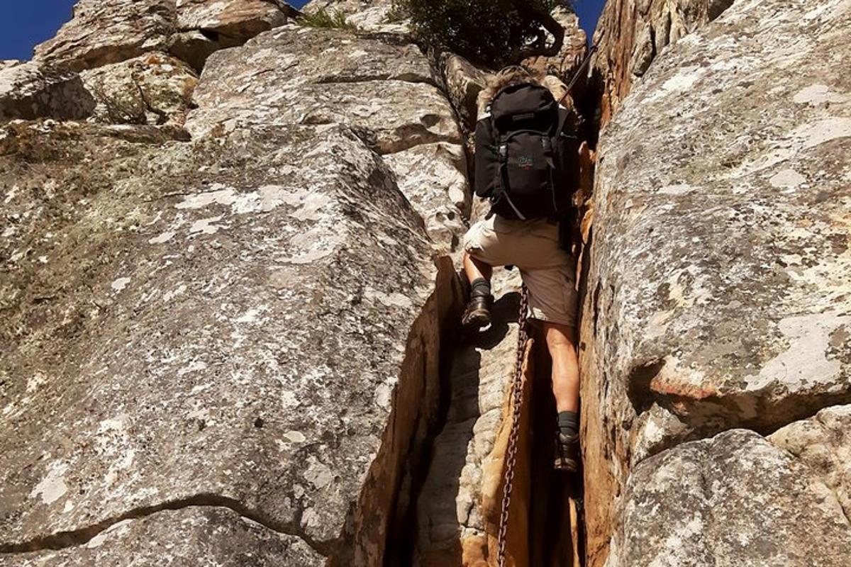Ένας άντρας με σακίδιο πλάτης σκαρφαλώνει σε ένα βραχώδες βουνό