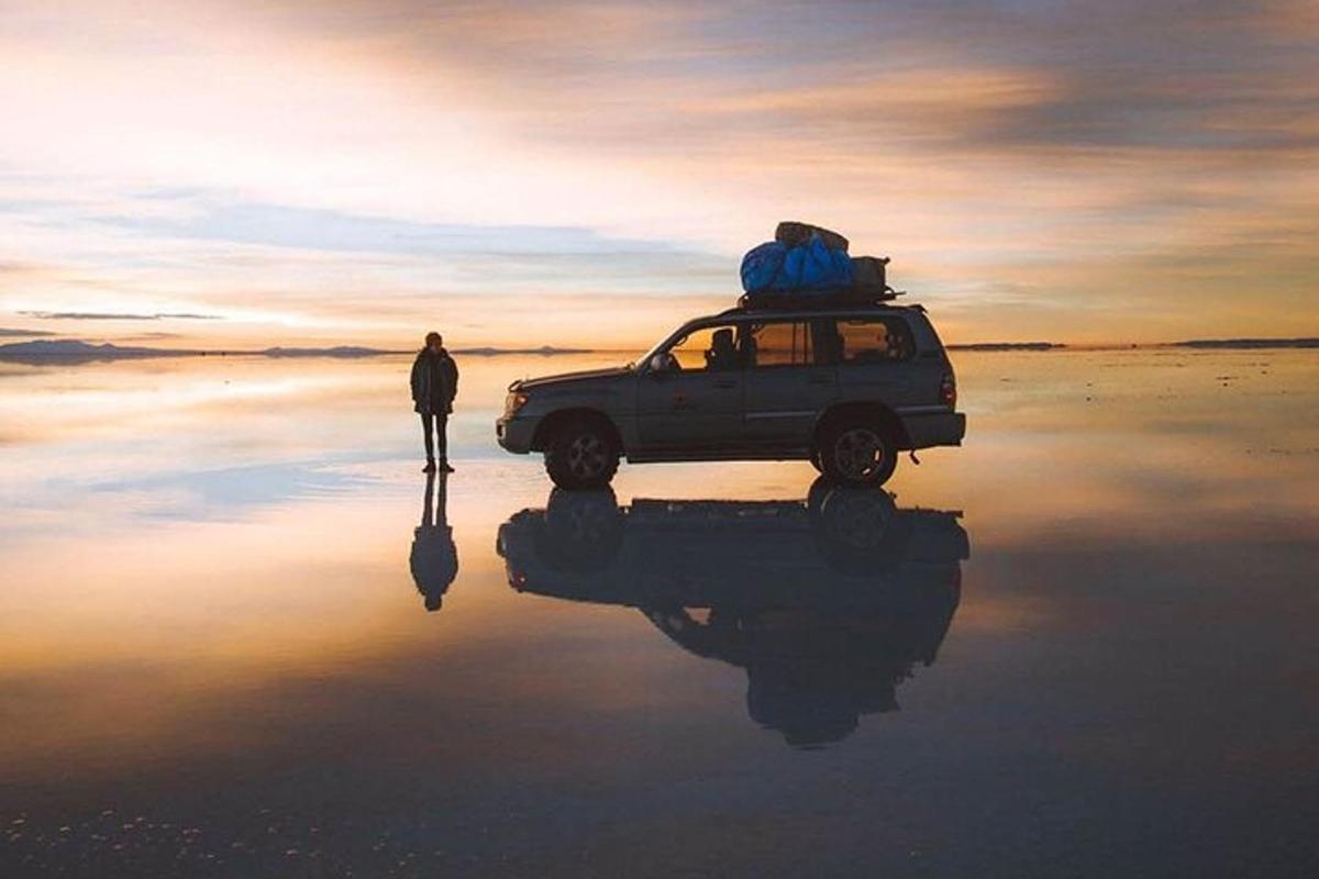 a person standing next to a car on the beach
