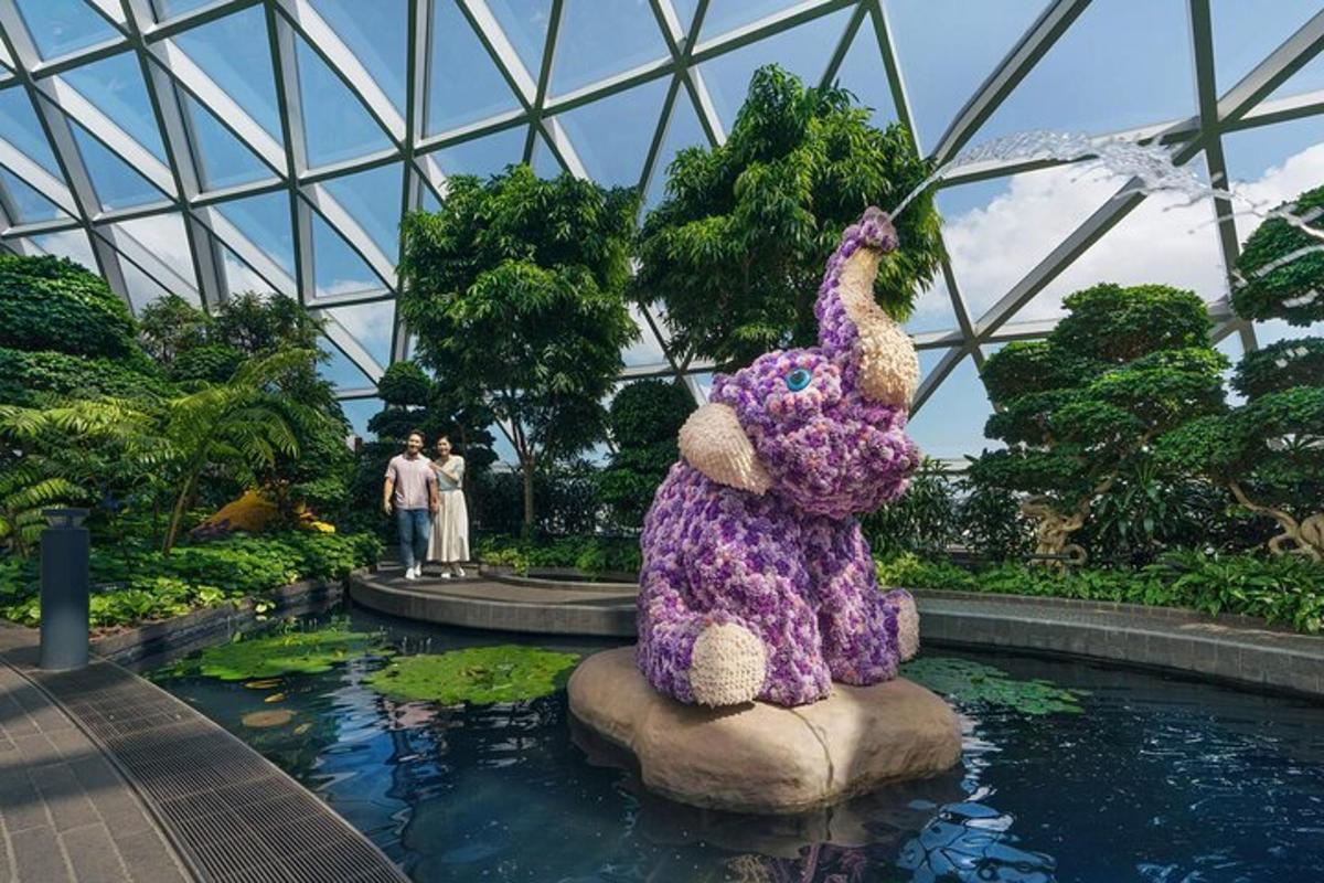 a large stuffed chicken sitting on a rock in a garden