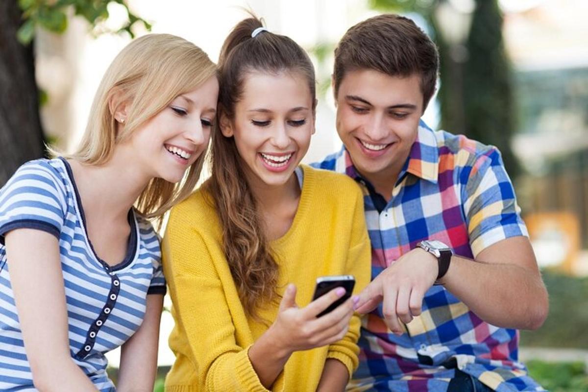 skupina tří lidí dívajících se na mobilní telefon