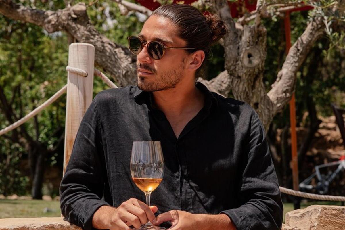 un uomo seduto a un tavolo con un bicchiere di vino
