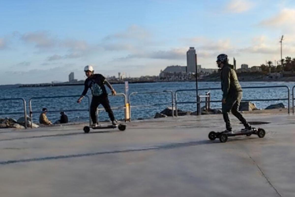 dua pria mengendarai skateboard di trotoar dekat air
