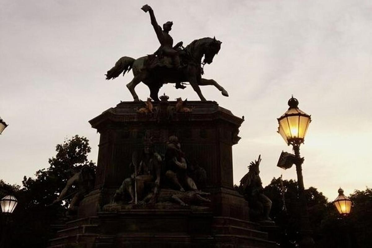 egy férfit ábrázoló szobor, amely lovagol egy utcai lámpa mellett