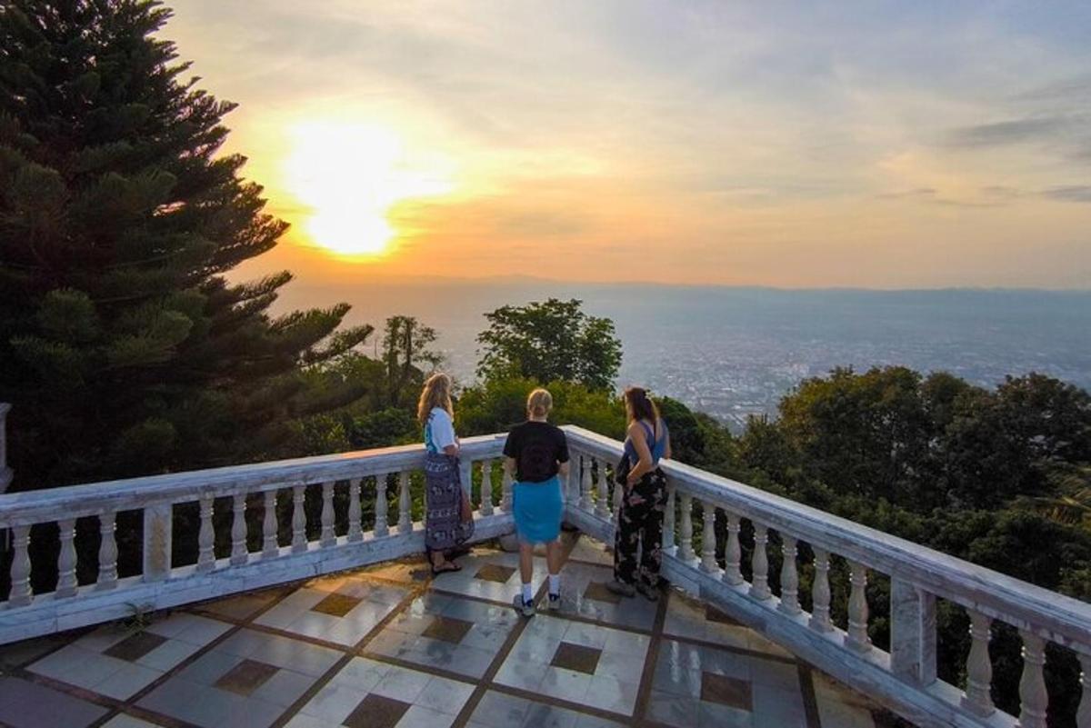 tres noies dretes en una cornisa mirant la posta de sol