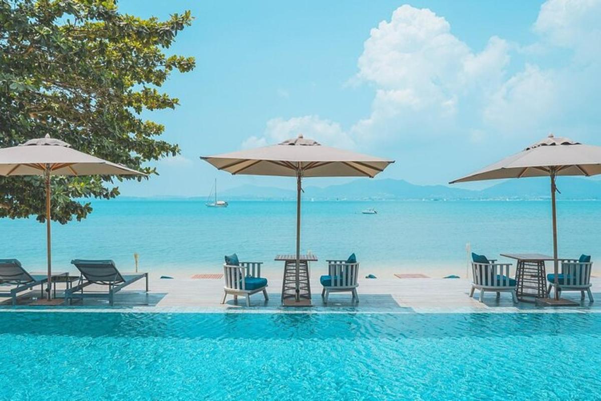 kolam renang dengan kerusi dan meja serta payung