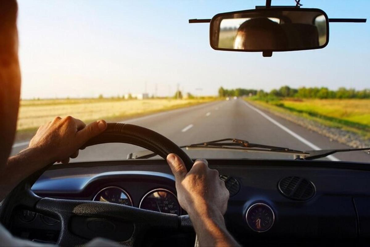un uomo alla guida di un'auto su una strada