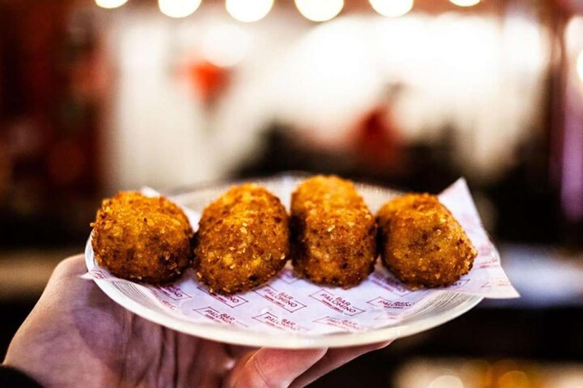 uma pessoa segurando um prato com quatro alimentos fritos