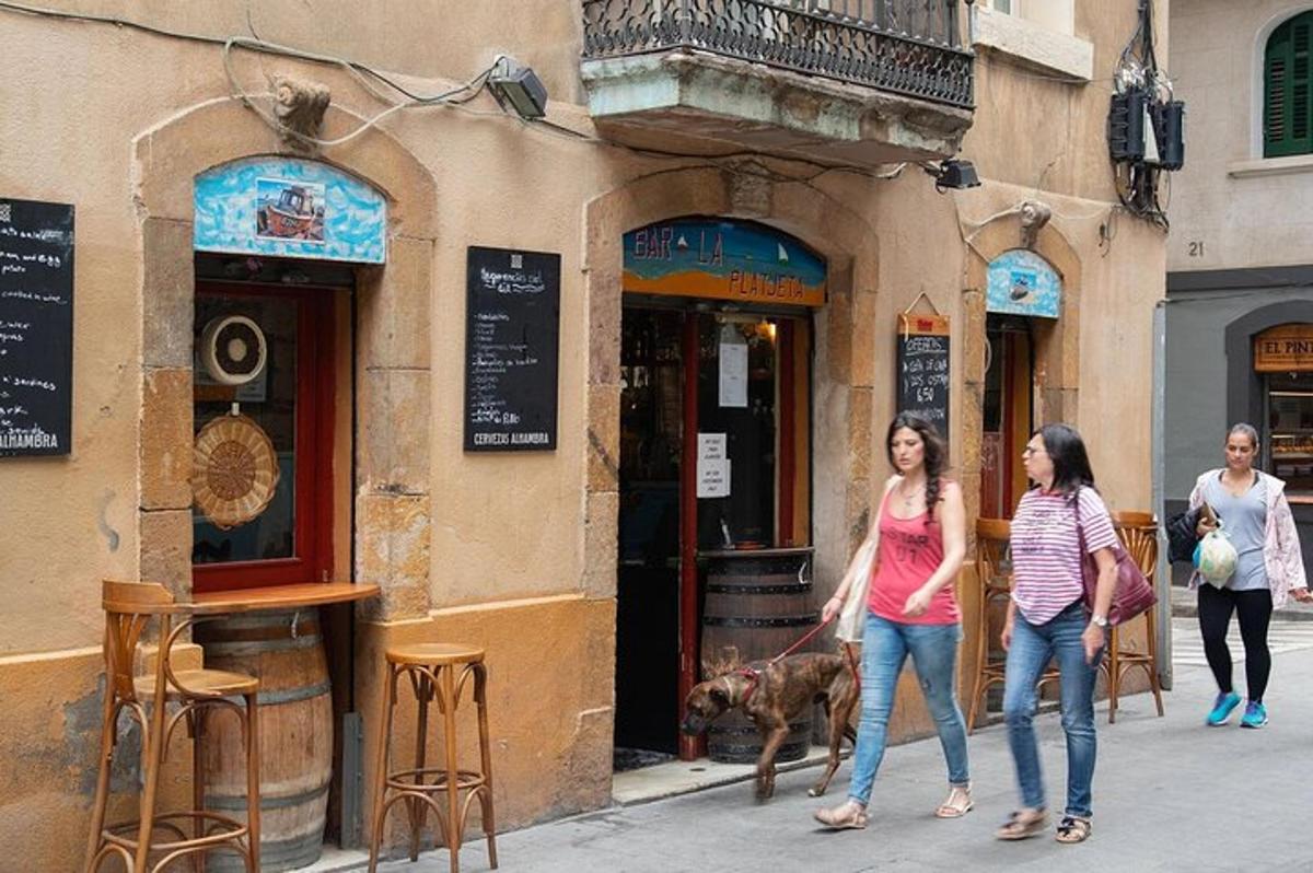 duas mulheres passeando com um cachorro em frente a um prédio