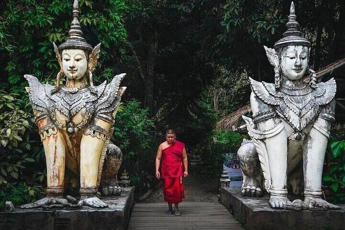 a man in a red dress walking between two statues