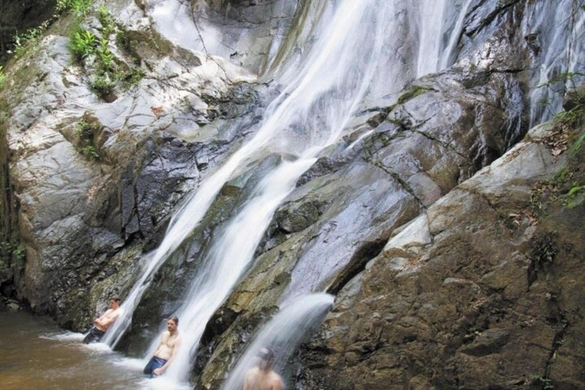 two people standing in the water at a waterfall