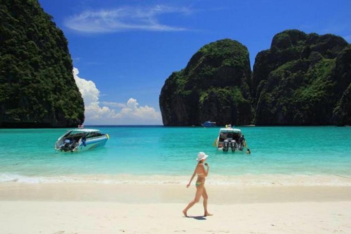 una donna che cammina su una spiaggia con due barche in acqua