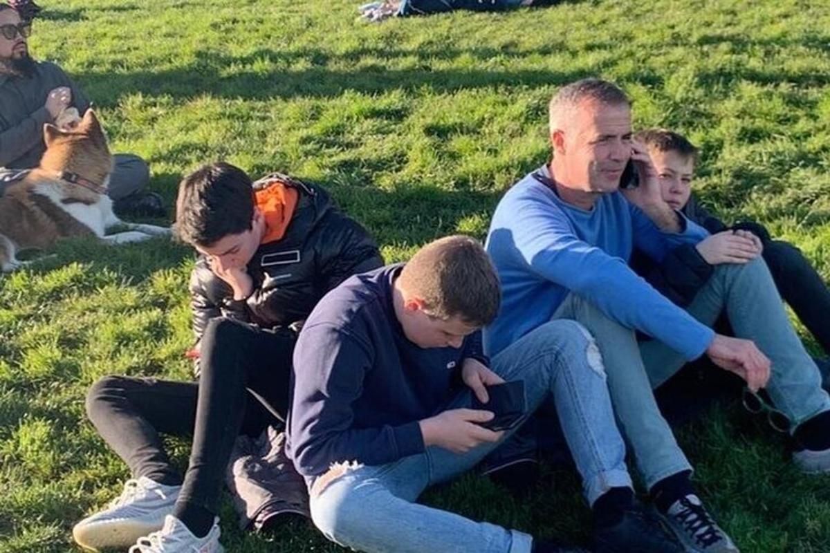 skupina lidí sedících na trávě