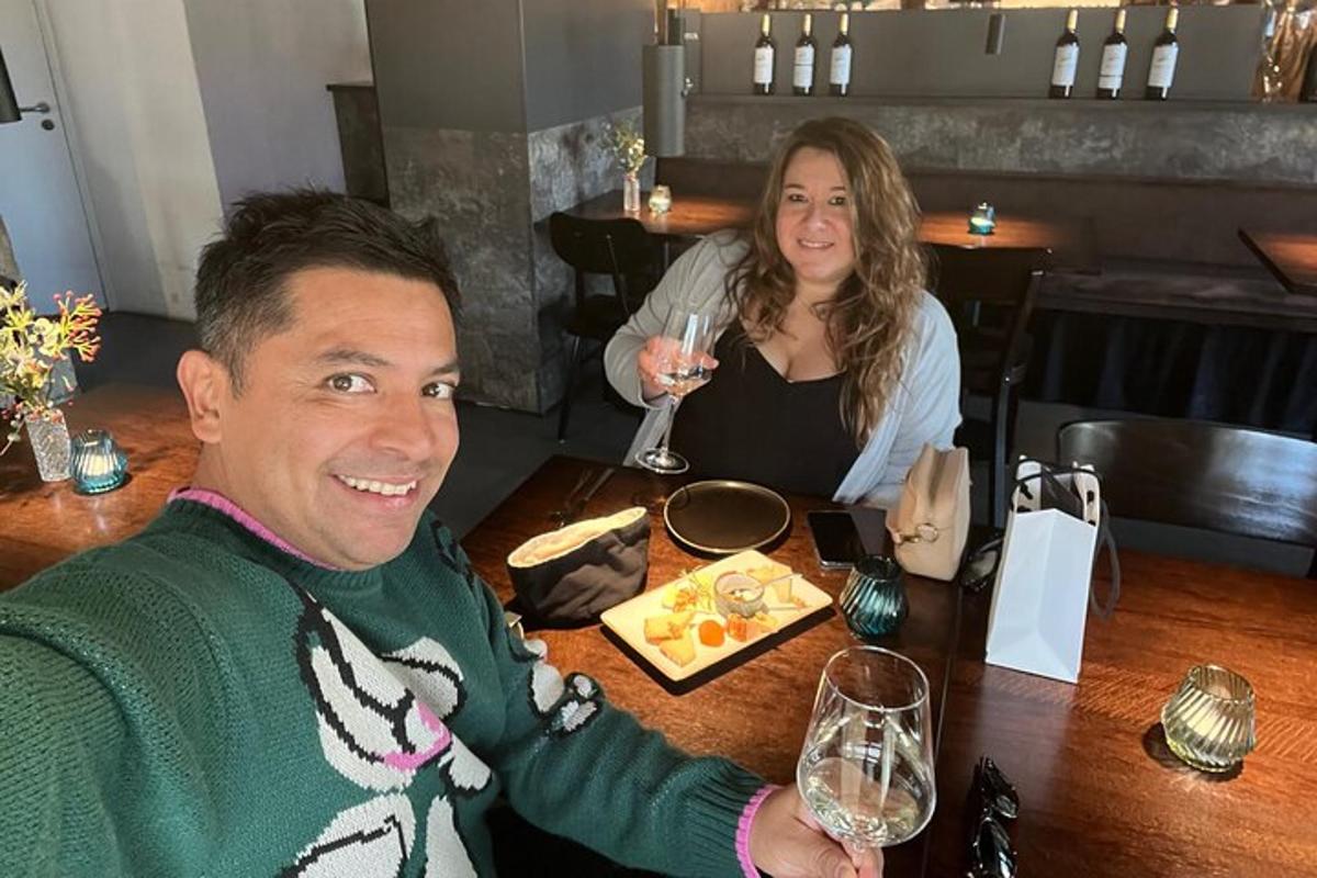 un bărbat și o femeie așezați la o masă cu pahare de vin