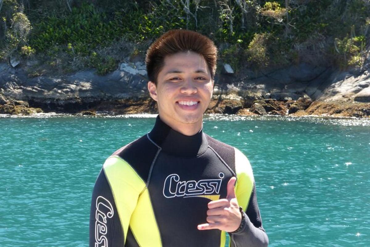 um jovem em uma roupa de mergulho segurando um polegar para cima