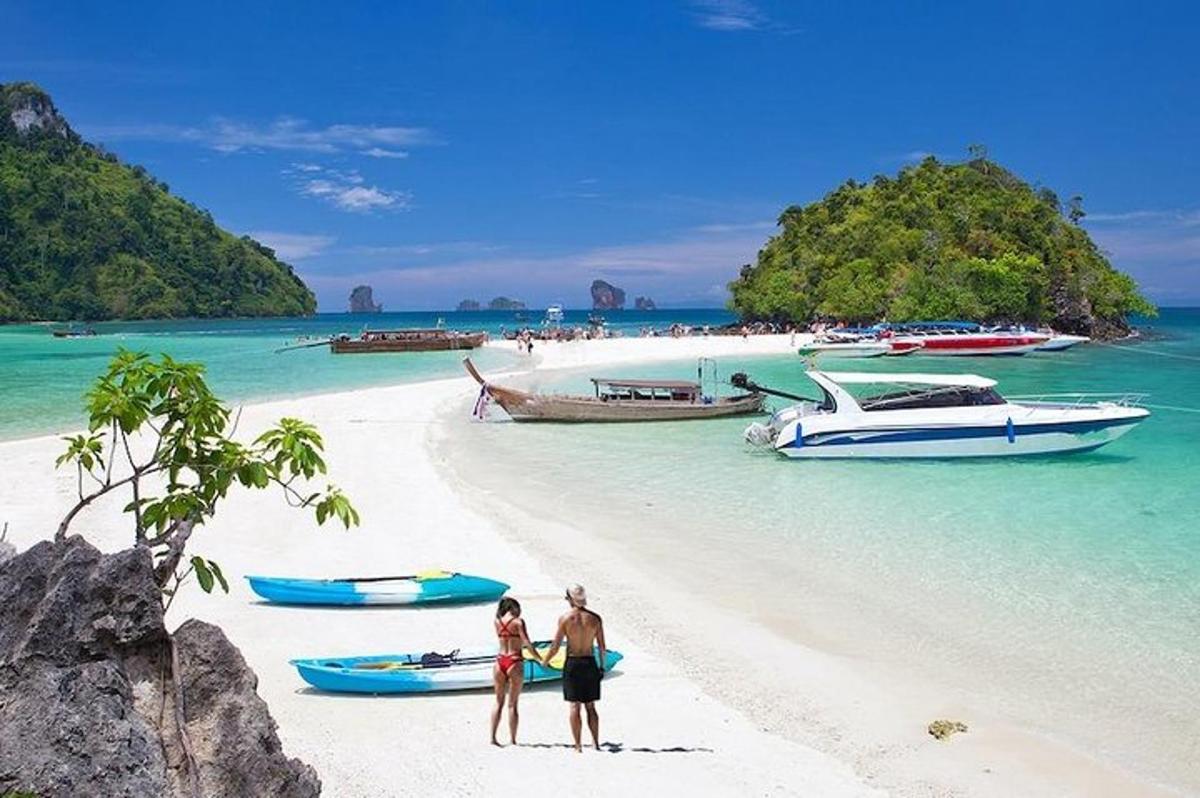 dua orang berdiri di pantai dengan bot di dalam air