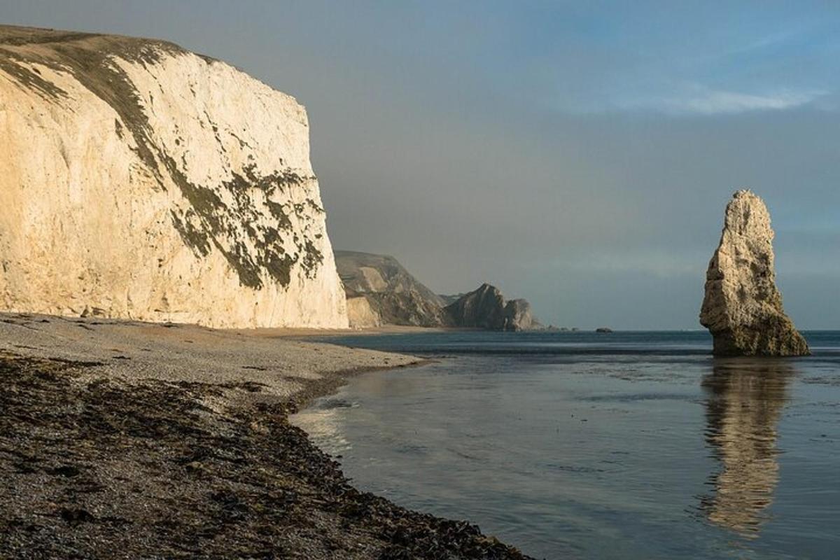 una grande roccia nell'acqua vicino a una spiaggia