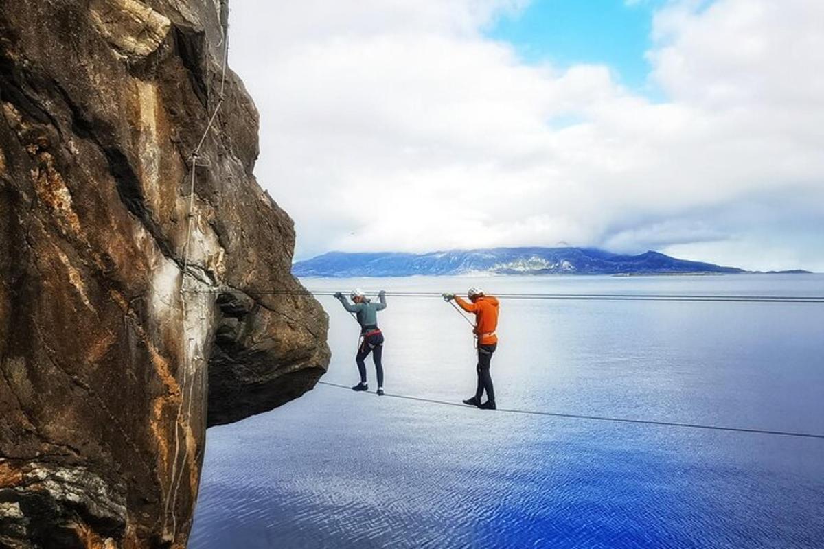 two people standing on a rope between two rocks in the water