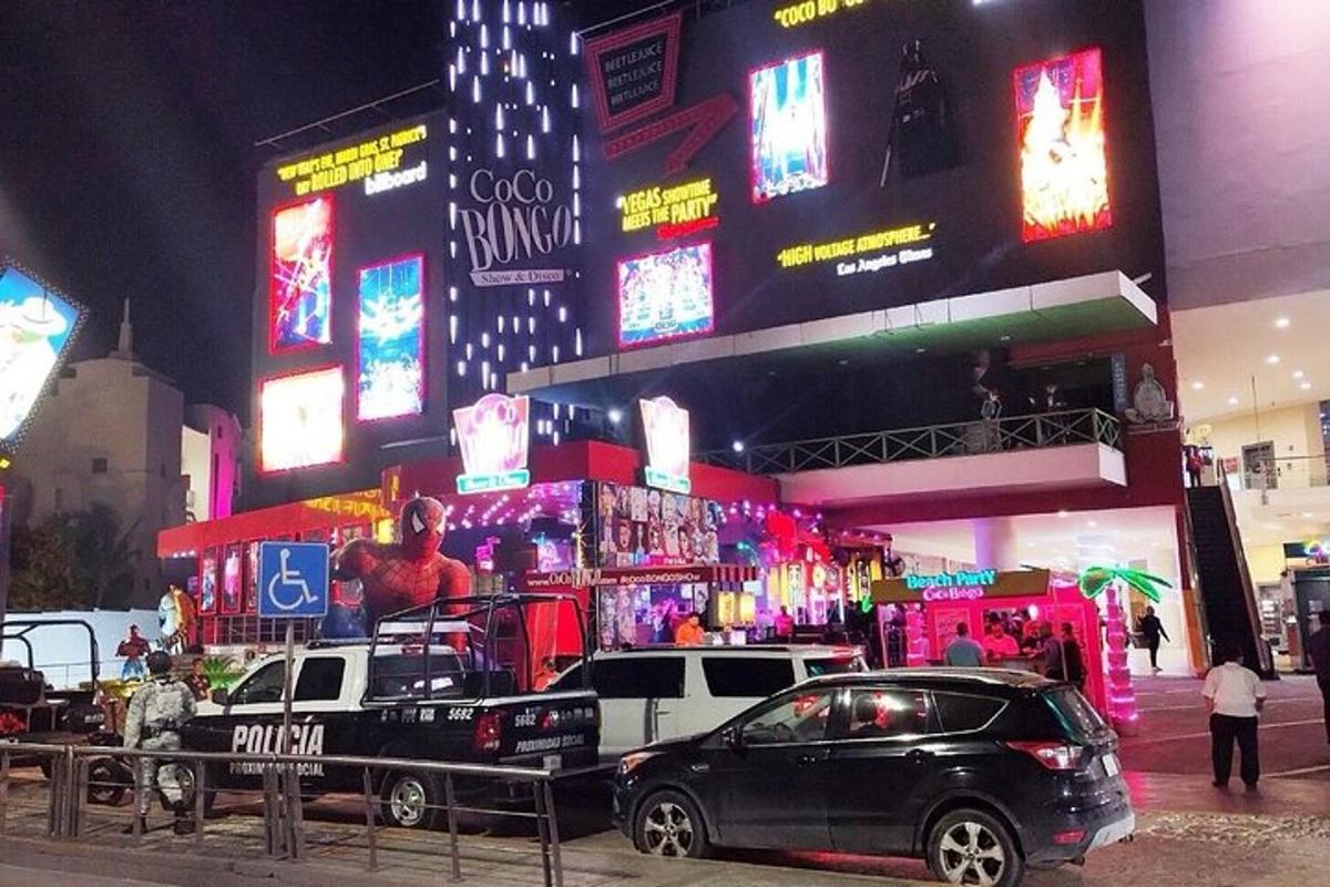 dwa samochody zaparkowane przed budynkiem z neonowymi szyldami