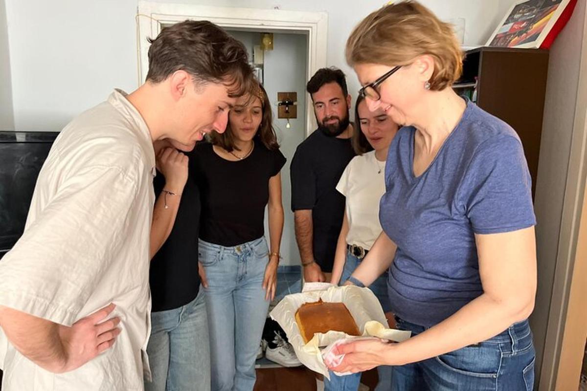 un grup de oameni care se uită la un bărbat care ține în mână un tort