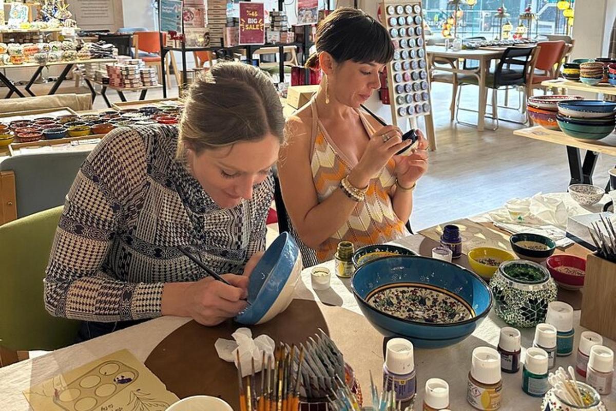 two women sitting at a table looking at their cell phones