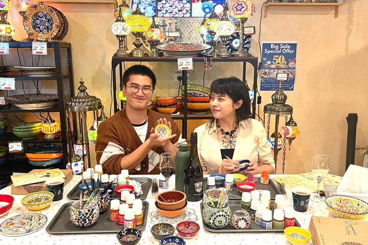 a man and a woman sitting at a table with ceramics