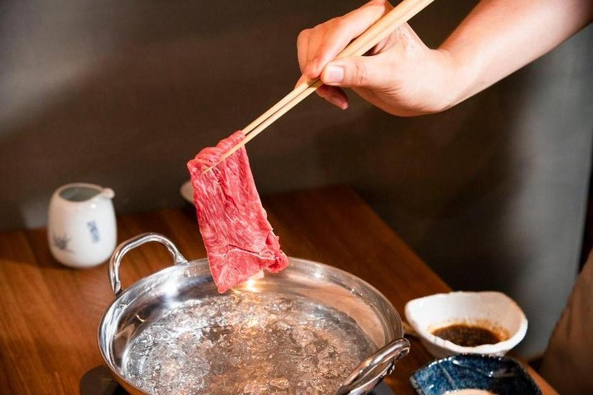 人が箸で鍋の中の肉をかき混ぜている