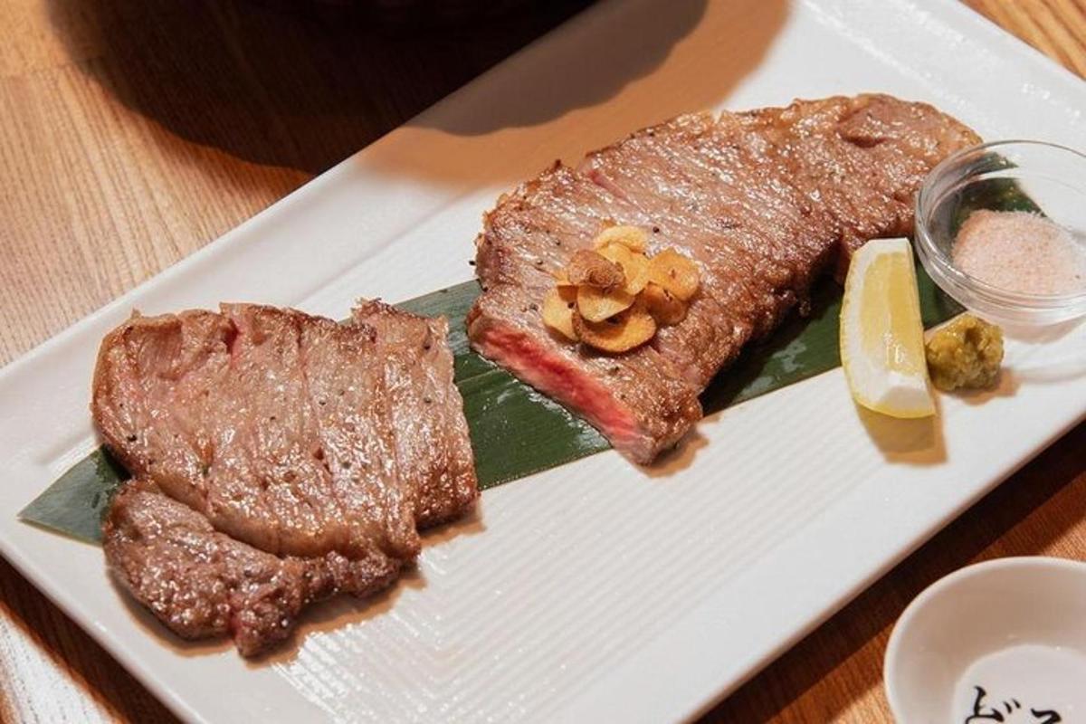 un plat blanc amb bistec i una peça de fruita