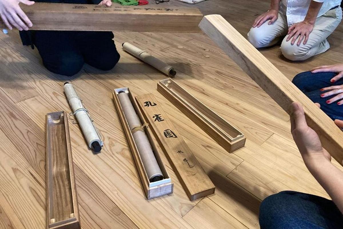 hópur fólks situr á gólfinu með tréstöngum
