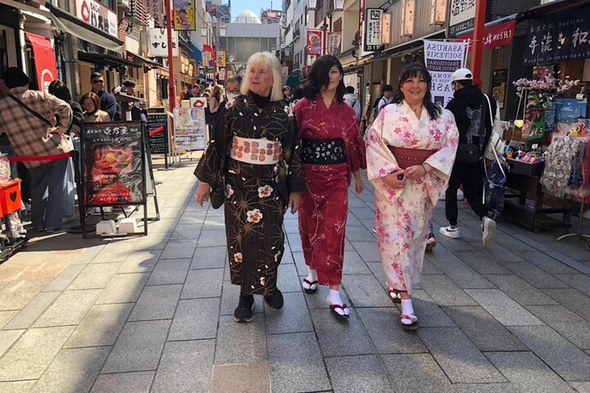 três mulheres caminhando por uma rua comercial usando quimonos