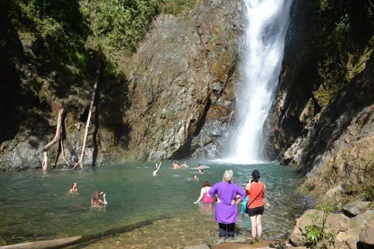 a group of people in the water near a waterfall