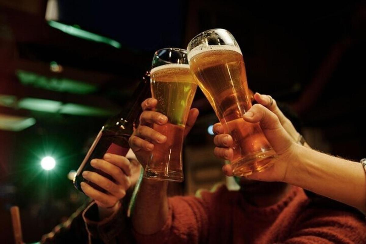 duas pessoas segurando copos de cerveja nas mãos