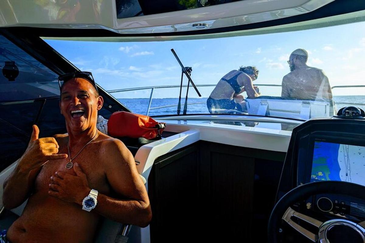 a shirtless man sitting in the cockpit of a boat