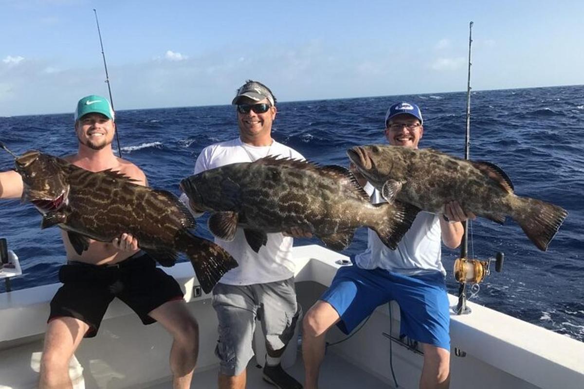 three men holding up a large fish on a boat