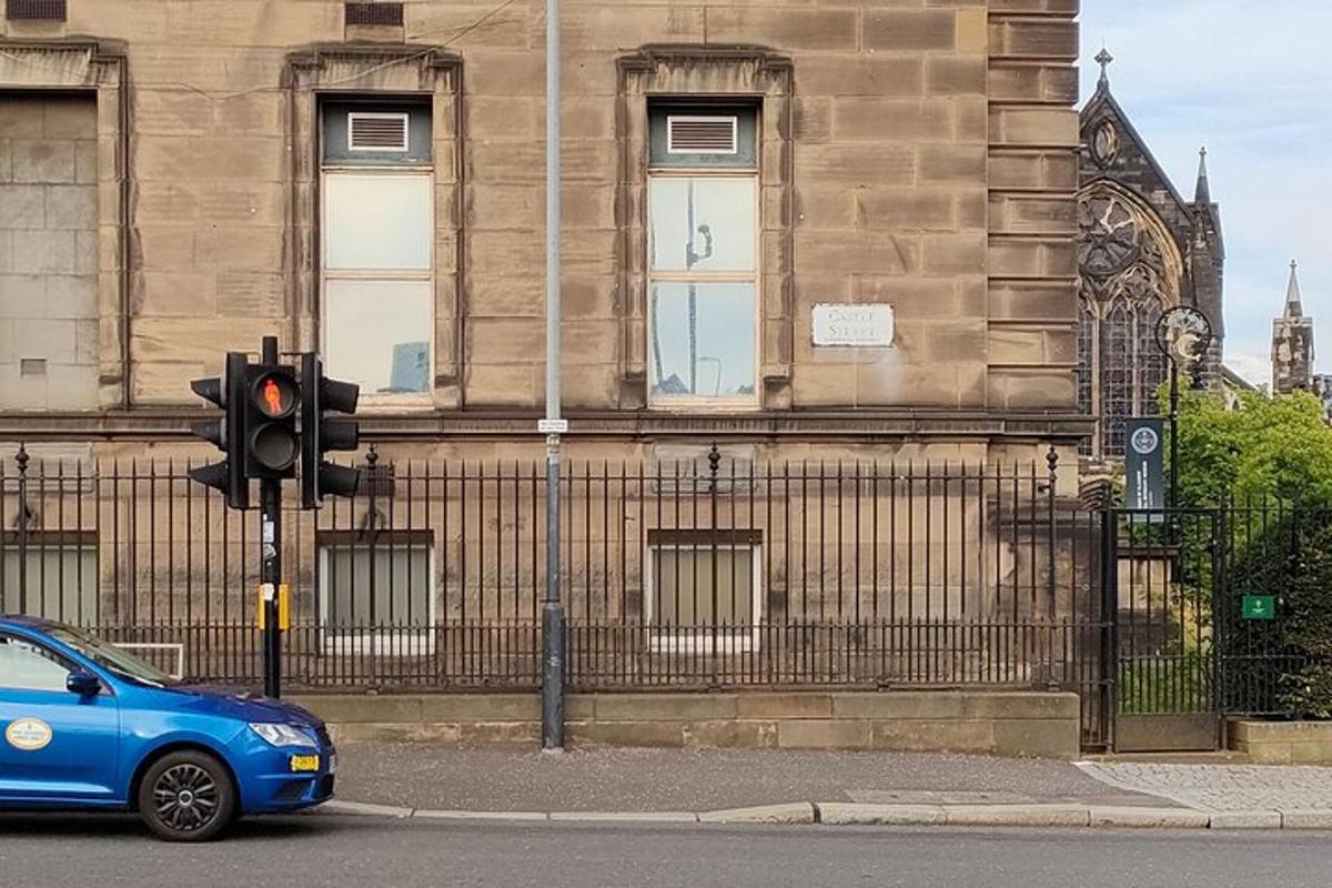 a blue car stopped at a traffic light in front of a building