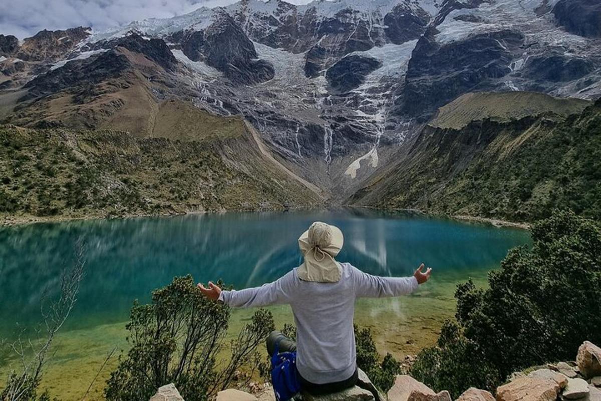 dues persones assegudes al cim d'una muntanya amb vistes a un llac