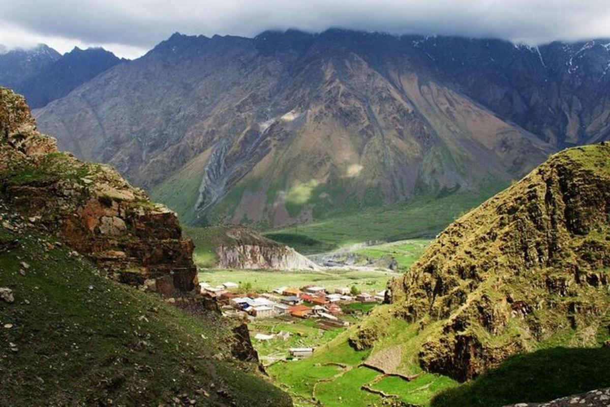 pemandangan lembah gunung dengan perkampungan di padang