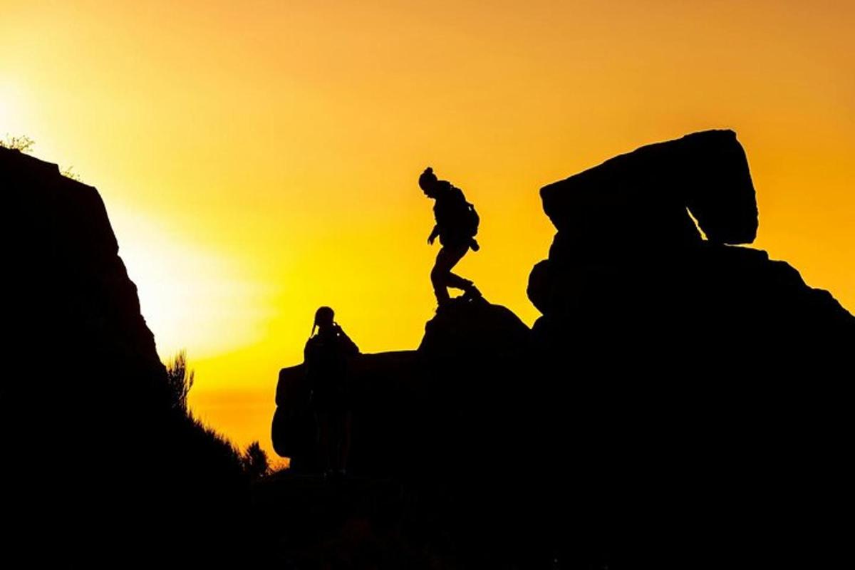 maður stendur á fjallstoppi við sólsetur